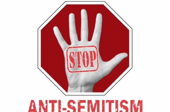 Denouncing Antisemitism 1 Graphic showing a raised hand with the word 'STOP' stamped on the palm, set against a red stop sign background, with the bold text 'ANTI-SEMITISM' below, symbolizing a message against antisemitism.